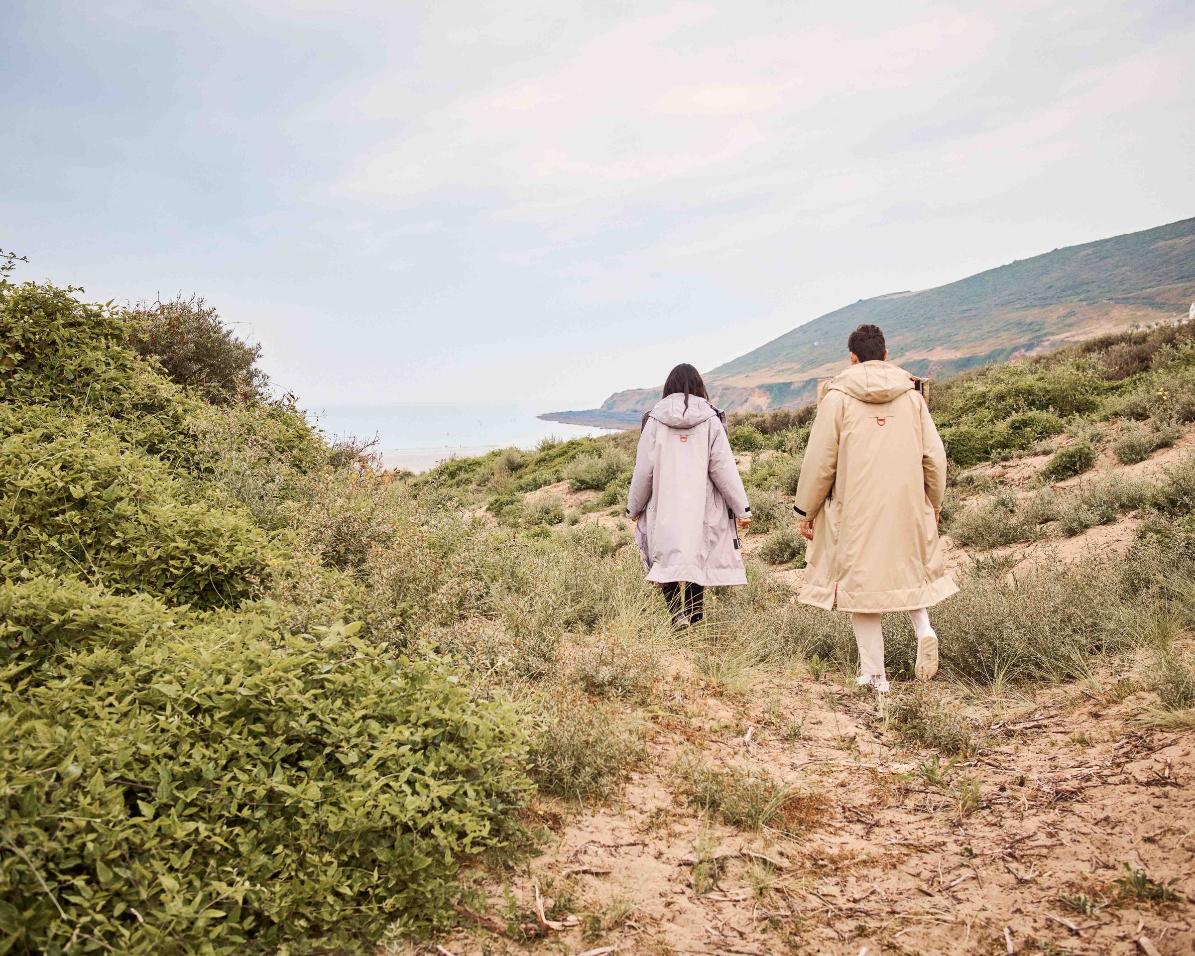 A man and a woman strolling on the Beautiful Devon beach on a Spring day wearing D-Robe dry robes. The versatility of the Beaufort Robe is truly remarkable, offering a multitude of applications. It can be used as a dry robe, a parka, a raincoat or as a fashionable oversized coat layered on the clothing of your choice.