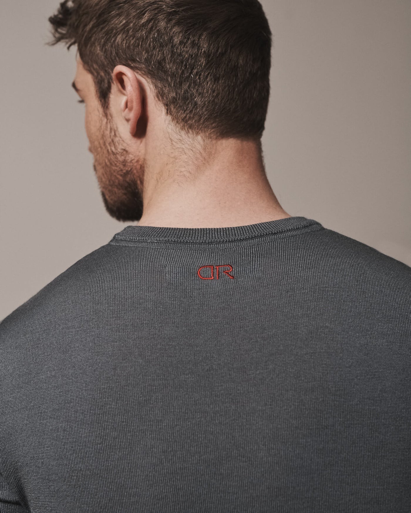 Our extra-fine merino wool crew neck jumpers for men and women in storm grey are made from a lightweight fabric and reactive natural fibre. Finished with our signature brand logo with red stitching. Ideal for layering under our waterproof dry robes for spectating touchdown sports or walking the dog.
