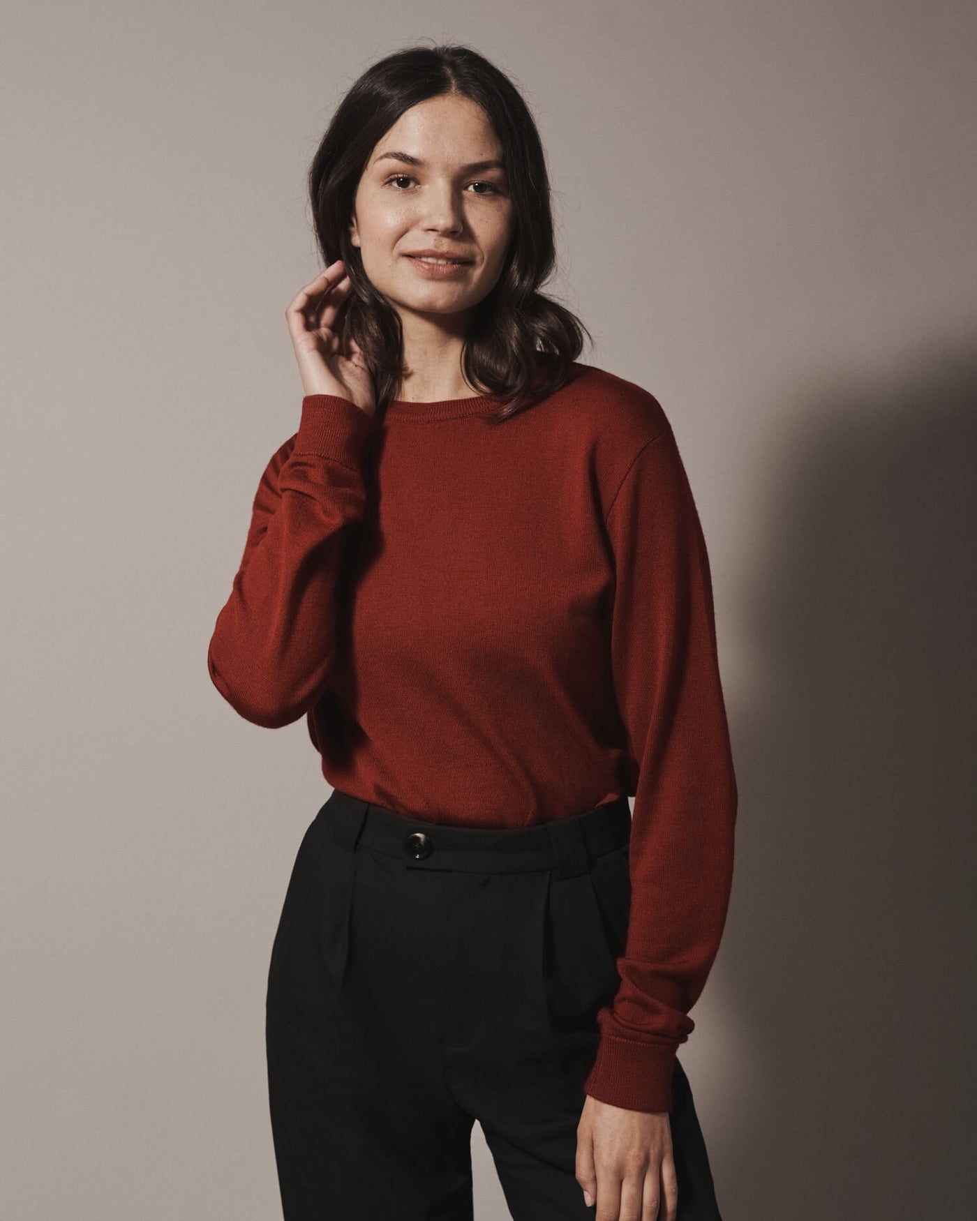 Female model wearing our unisex extra-fine merino wool crew neck jumper, made from a lightweight fabric and reactive natural fibre. Ideal for layering under our waterproof dry robes for spectating touchdown sports or walking the dog. The perfect addition to any minimalist capsule wardrobe.