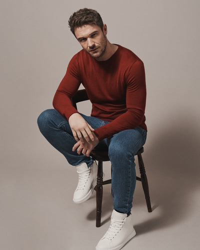 Model wearing our unisex extra-fine merino wool crew neck jumper in maroon red, made from a lightweight fabric and reactive natural fibre. Ideal for layering under our waterproof dry robes for smart city commute attire. The perfect addition to any minimalist capsule wardrobe.