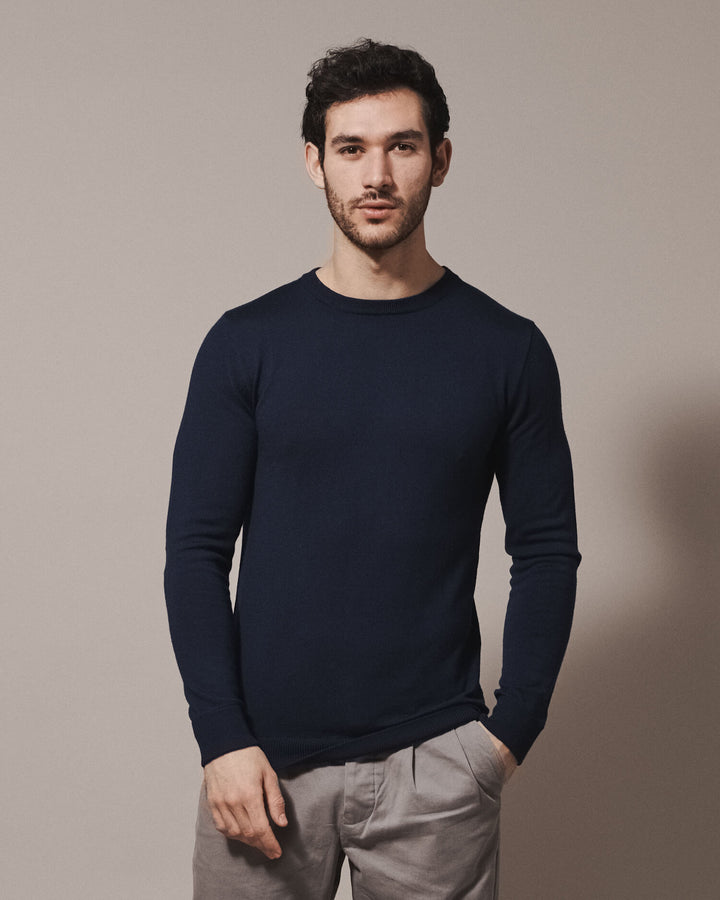 Model wearing our unisex extra-fine merino wool crew neck jumper, made from a lightweight fabric and reactive natural fibre. Ideal for layering under our waterproof dry robes for spectating touchdown sports or walking the dog. The perfect addition to any minimalist capsule wardrobe.