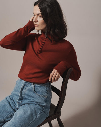 Model wearing our unisex extra-fine merino wool 1/4 zip jumper in maroon red, made from a lightweight fabric and reactive natural fibre. Ideal for layering under our waterproof dry robes for spectating touchdown sports or walking the dog. The perfect addition to any minimalist capsule wardrobe.