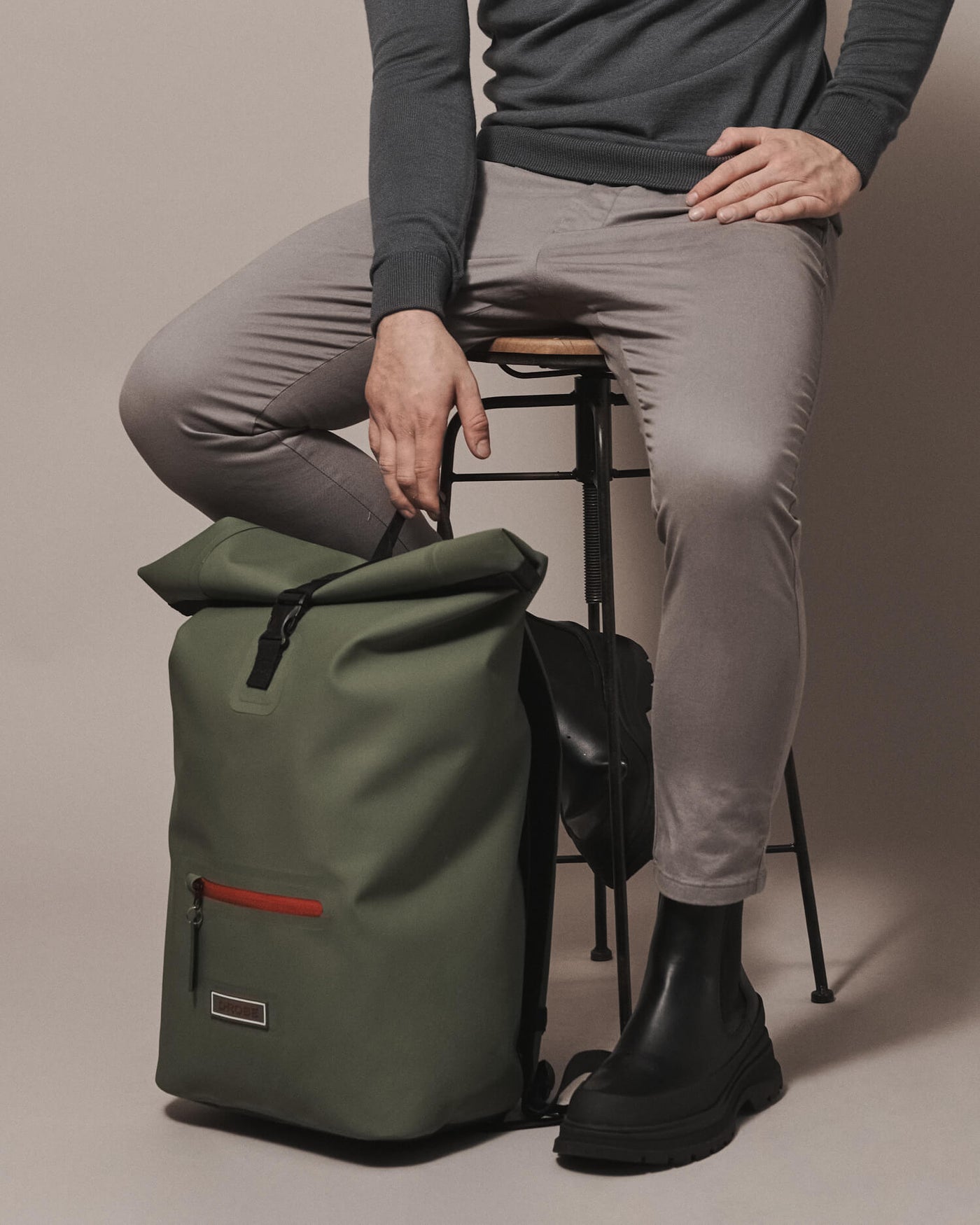 Model with our moss green roll-top rucksack. This rucksack is a must-have for any sport Robe wearer, commuter and traveller. Made from durable, waterproof and sustainable TPU and fitted with extra storage.